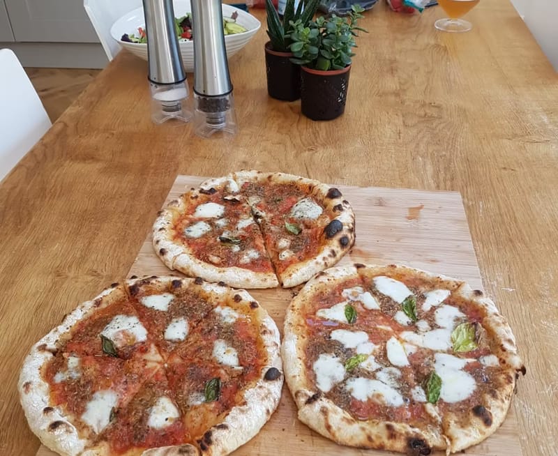 Three sourdough margheritas with blistered crusts on a wooden board